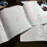 入社3ヶ月の新人の図面に、手描き図や赤ペンで細かく修正指示（赤字）を入れた、構造設計のチェック風景