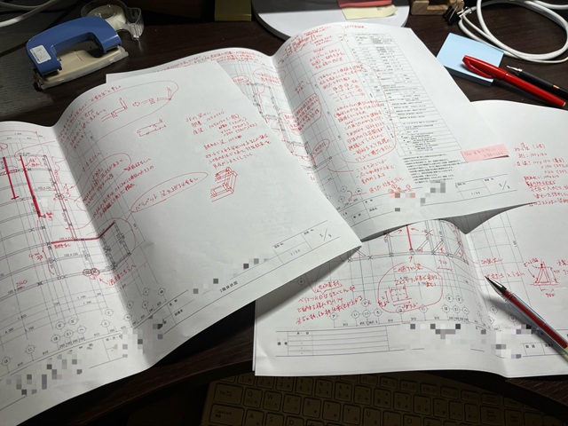 入社3ヶ月の新人の図面に、手描き図や赤ペンで細かく修正指示(赤字)を入れた、構造設計のチェック風景